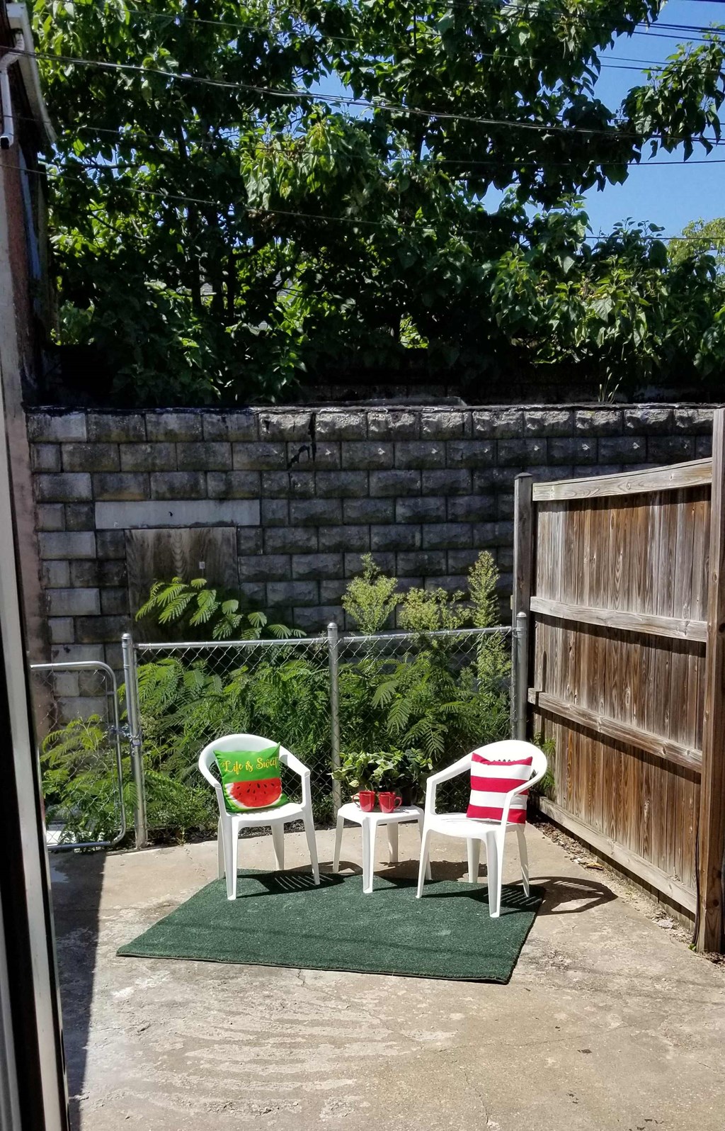 a patio with two chairs and a table and a fence