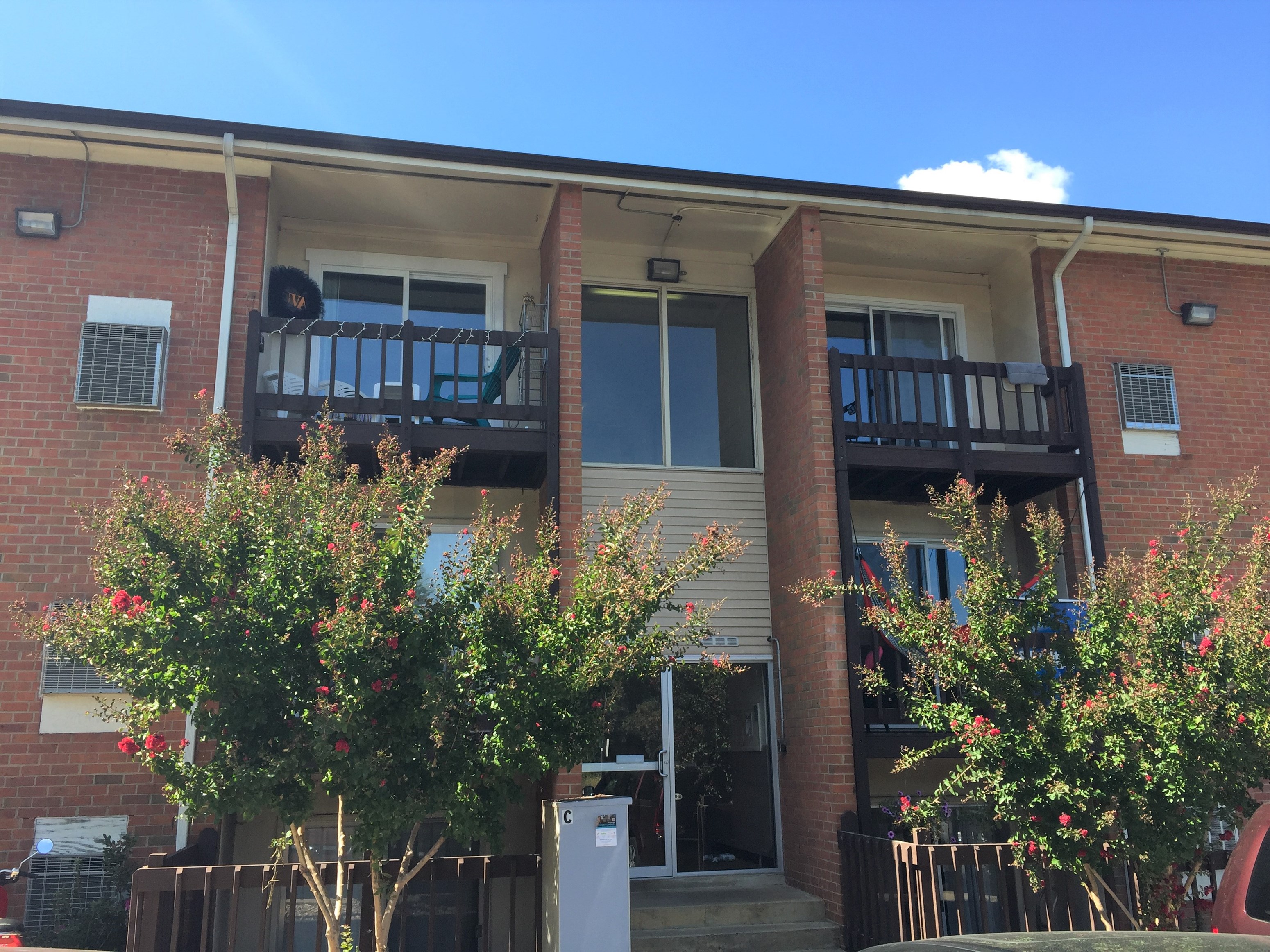 the front of a brick house with two balconies and trees