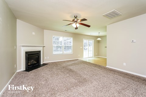 A spacious living room with a fireplace and a ceiling fan.
