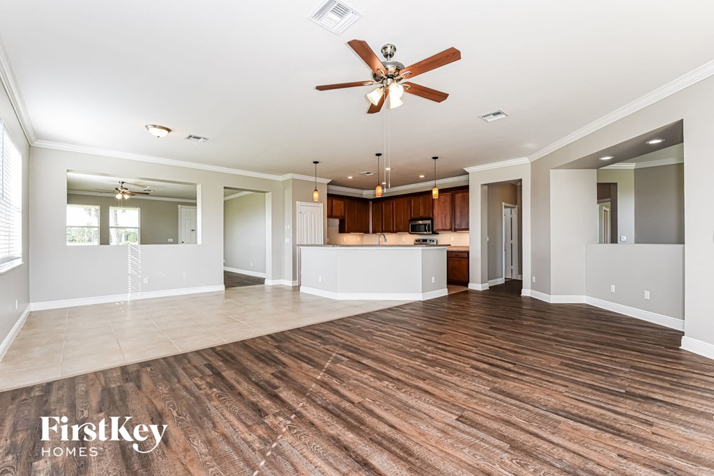 A spacious room with a ceiling fan and wooden flooring.