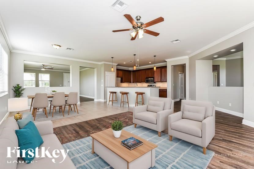 A living room with a ceiling fan and a dining table with chairs.