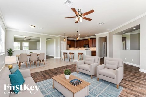 A living room with a ceiling fan and a dining table with chairs.