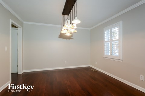 a dining room with a wood floor and white walls and a chandelier