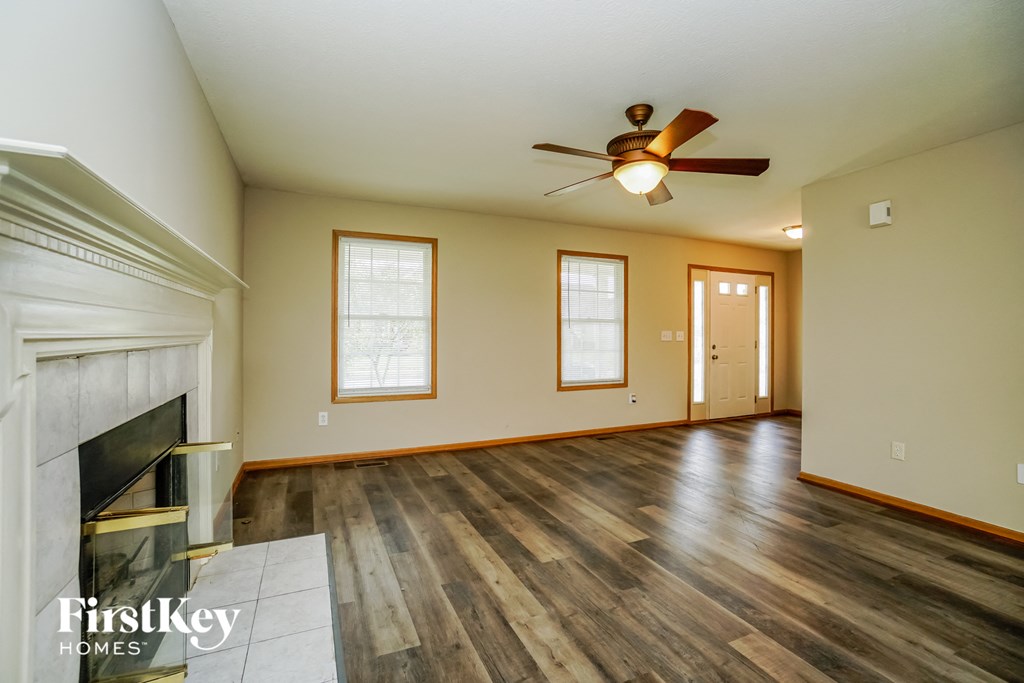 A spacious room with a fireplace and wood flooring.