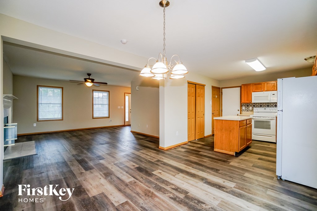 A kitchen with wooden floors and a white refrigerator.