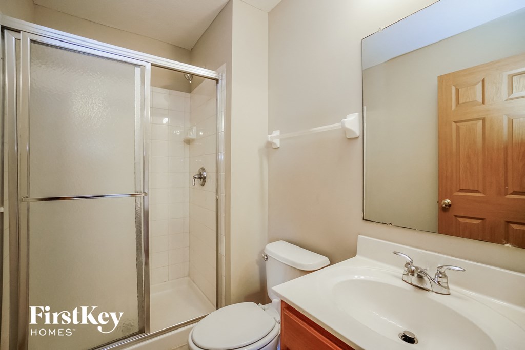 A bathroom with a toilet, sink, and mirror.