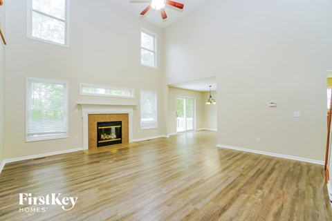 A spacious room with a fireplace and wooden flooring.