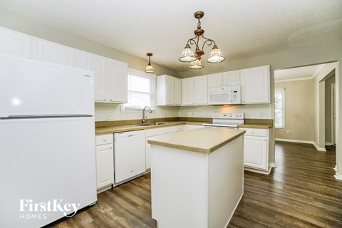 A kitchen with white cabinets and a white fridge.