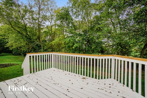 A wooden deck with a railing and trees in the background.