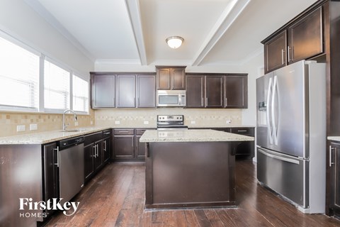 A kitchen with dark wood cabinets and a stainless steel refrigerator.