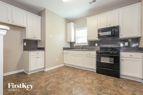 A kitchen with white cabinets and a black oven.