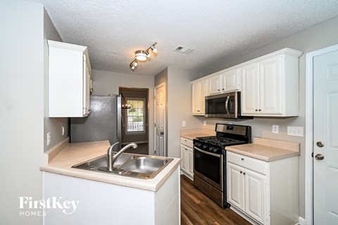 A kitchen with white cabinets and a stove top oven.
