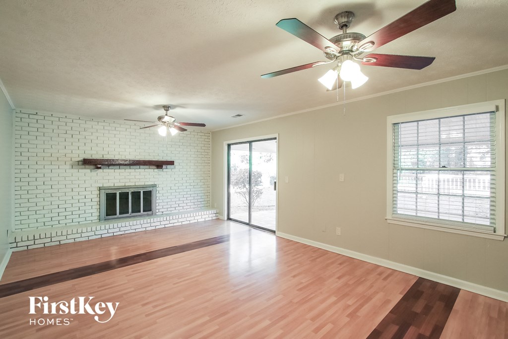 A room with a ceiling fan and a fireplace in a house.