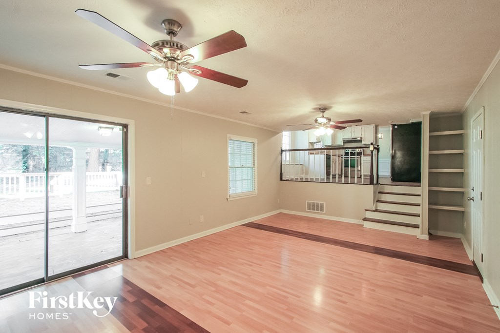 A spacious room with a ceiling fan and wooden flooring.