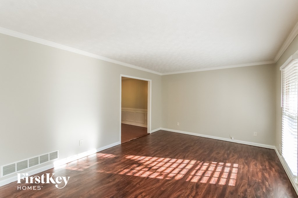 A room with wooden flooring and a window letting in sunlight.