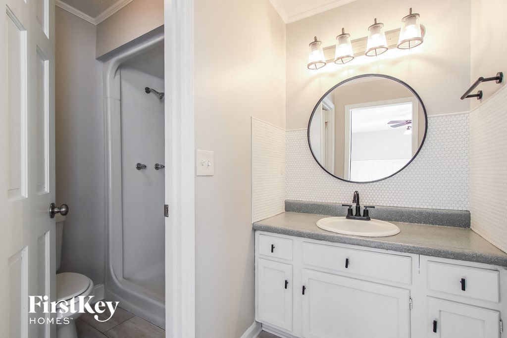 A bathroom with a white sink and a round mirror.