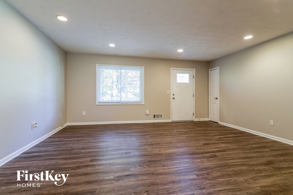 the spacious living room with wood flooring and a window