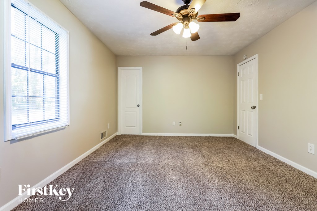 an empty living room with a ceiling fan and a window