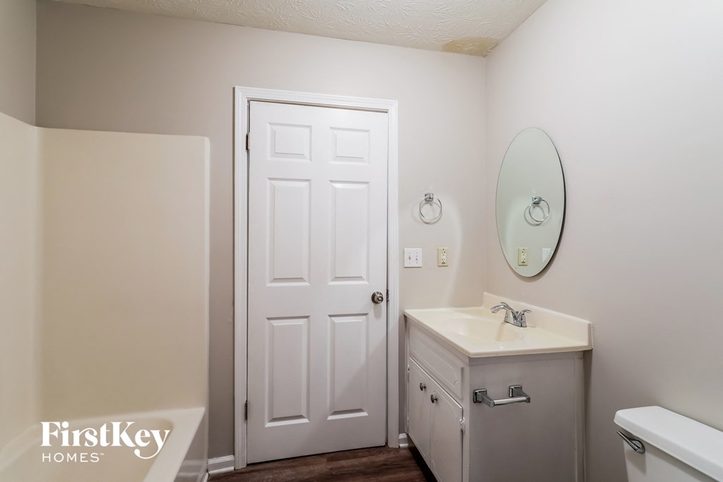 a bathroom with a white door and a sink and a mirror