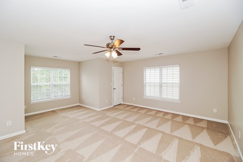 A spacious room with a fan and a carpeted floor.