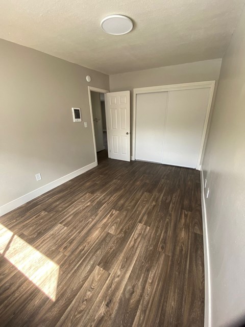 a living room with wood flooring and a door into a bedroom