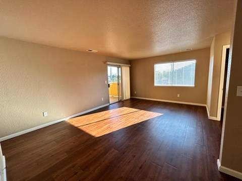 an empty living room with hard wood floors and a window