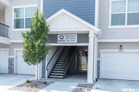 the front of a building with a garage door and stairs