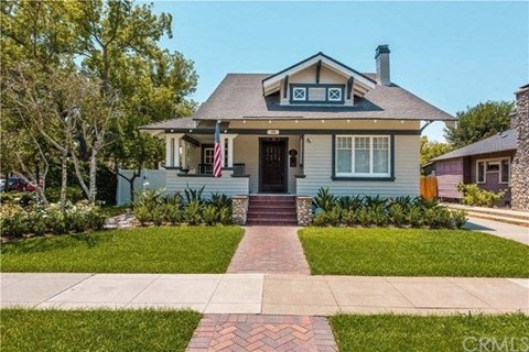 A house with a blue front and a flag on the front porch.