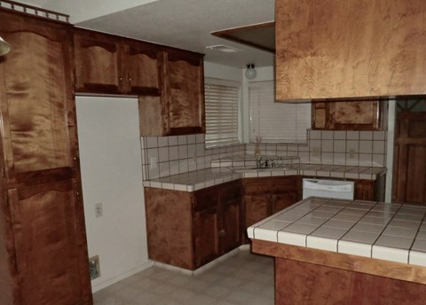 an empty kitchen with wooden cabinets and tiled counter tops