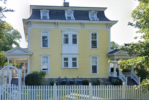 a yellow house with a white fence in front of it