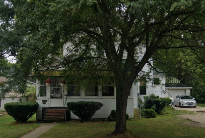 A white house with a tree in front of it.
