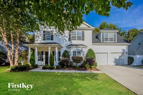A large, well-maintained house with a white front porch and a driveway.