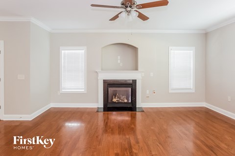 A living room with a fireplace and a ceiling fan.