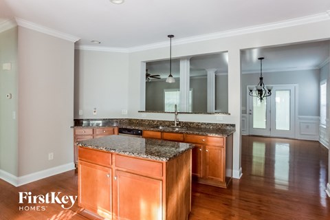 A kitchen with a granite countertop and wooden cabinets.