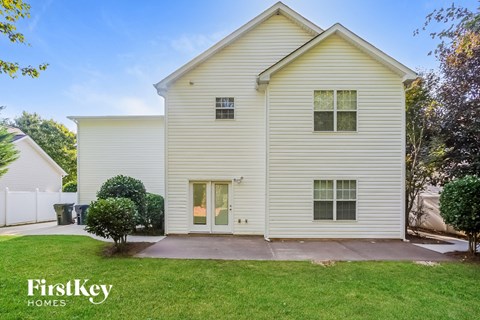 A two-story house with a white exterior and a small front yard.
