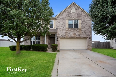 a brick house with a white garage door and a tree