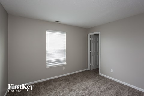 a bedroom with white carpet and a window and a door