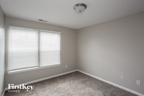 a bedroom with two windows and a carpeted floor