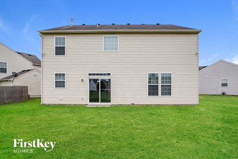 the back of a white house with a green lawn