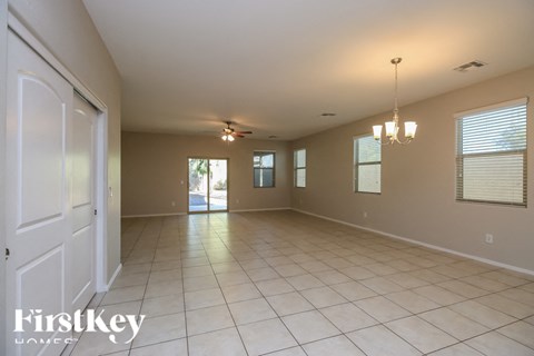 A spacious room with a white door and a chandelier hanging from the ceiling.