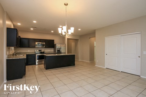 A spacious kitchen with black cabinets and a white door.