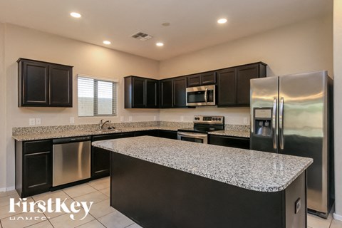 A modern kitchen with a granite countertop and stainless steel appliances.