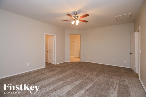 A room with a carpeted floor and a ceiling fan.