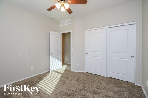A room with a carpeted floor and a ceiling fan.