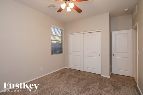 A room with a carpeted floor and a ceiling fan.