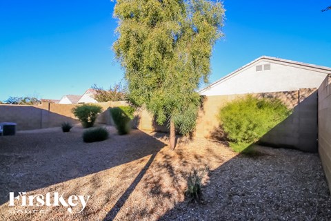A gravel area with a tree and a house in the background.