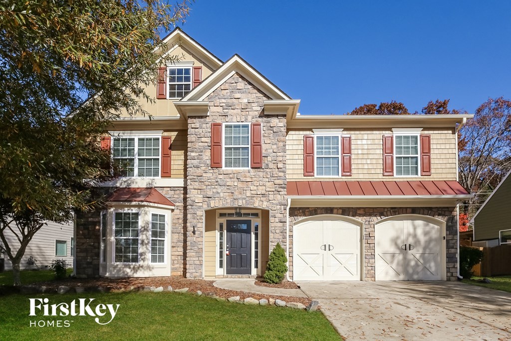 A house with a stone facade and a red roof is for sale by FirstKey Homes.
