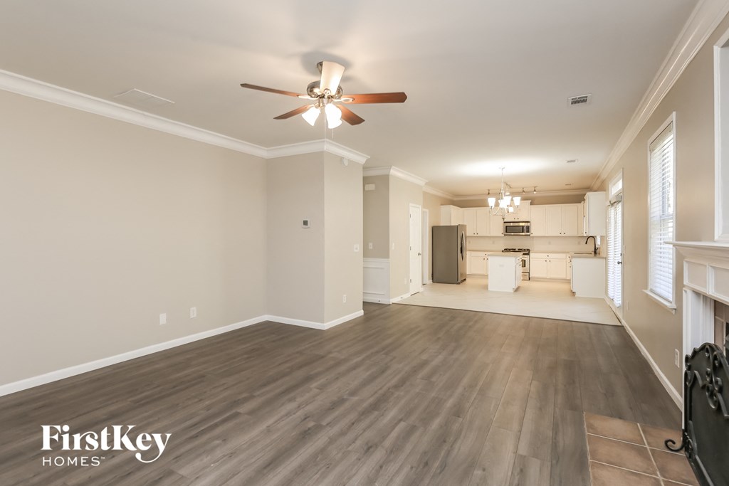 A spacious room with a ceiling fan and wooden flooring.