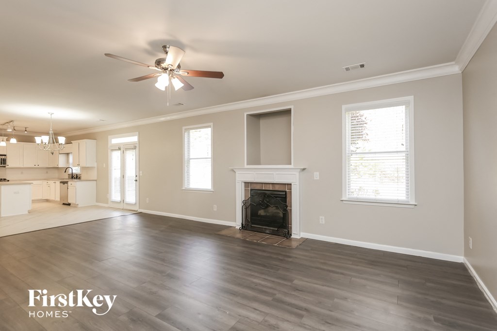 A spacious living room with a fireplace and a ceiling fan.