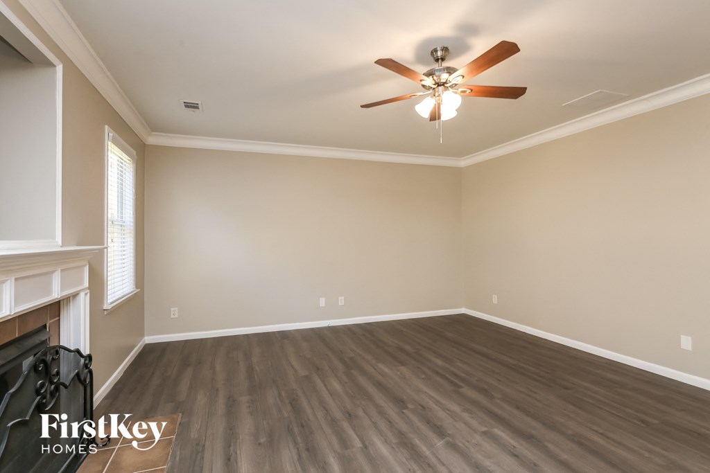 A room with a ceiling fan and wooden flooring.